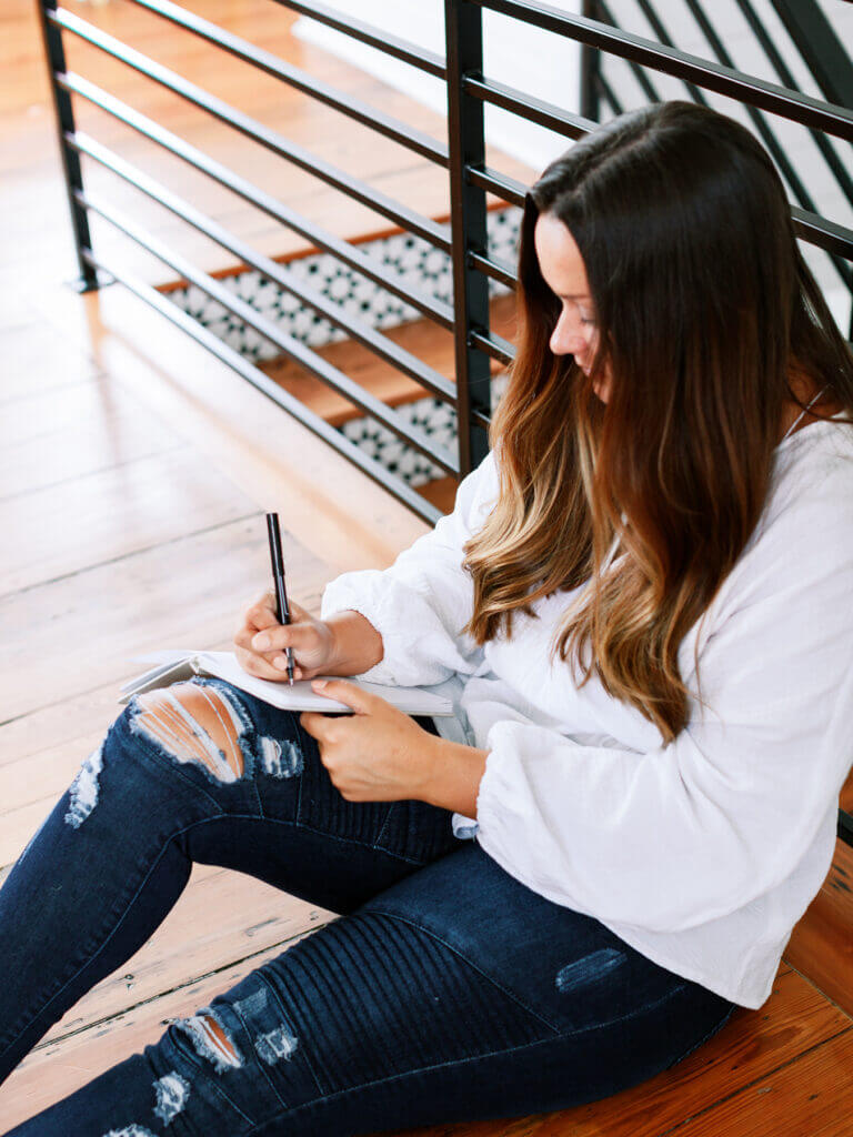 Female taking notes while searching customer research methods.