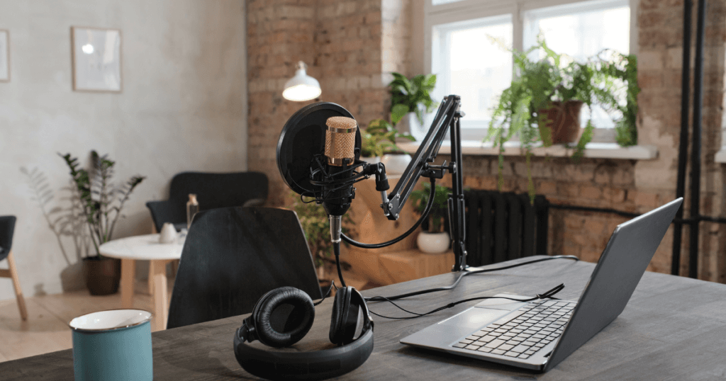 A home office with a microphone, laptop, and headphones set up for recording an evergreen podcast.