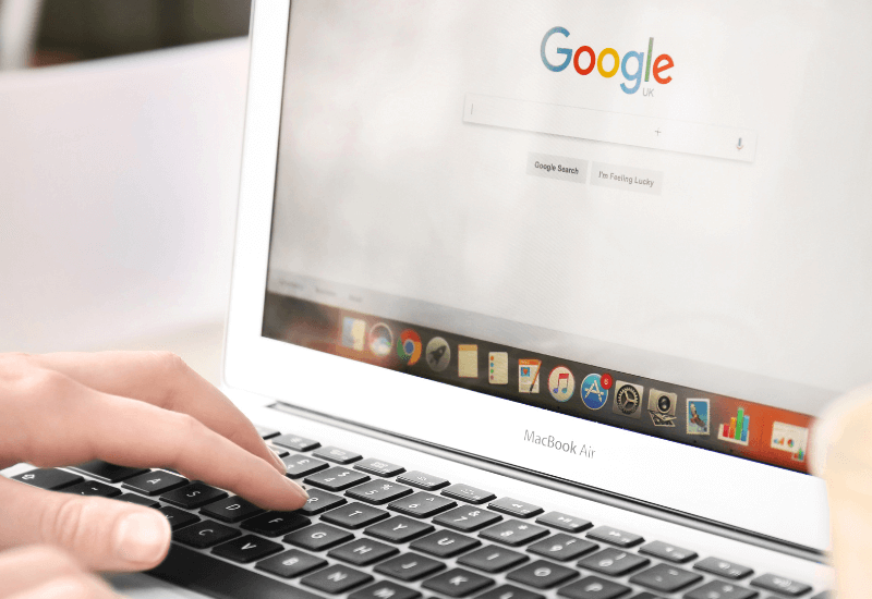 hands typing in a google search bar on a laptop