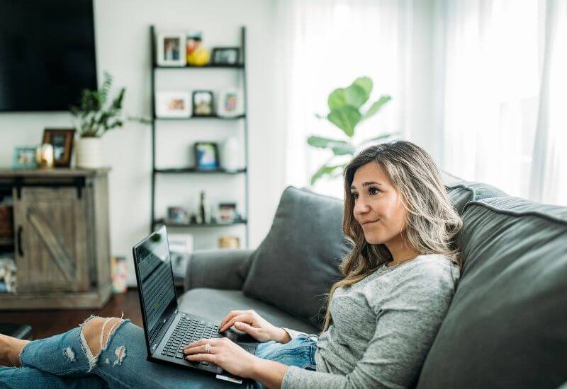  A Mompreneur working on her laptop while relaxing on the couch.